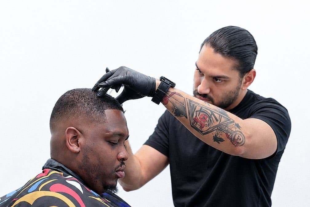 Miguel perfilando el cabello de un cliente, con la máquina en la mano enguantada